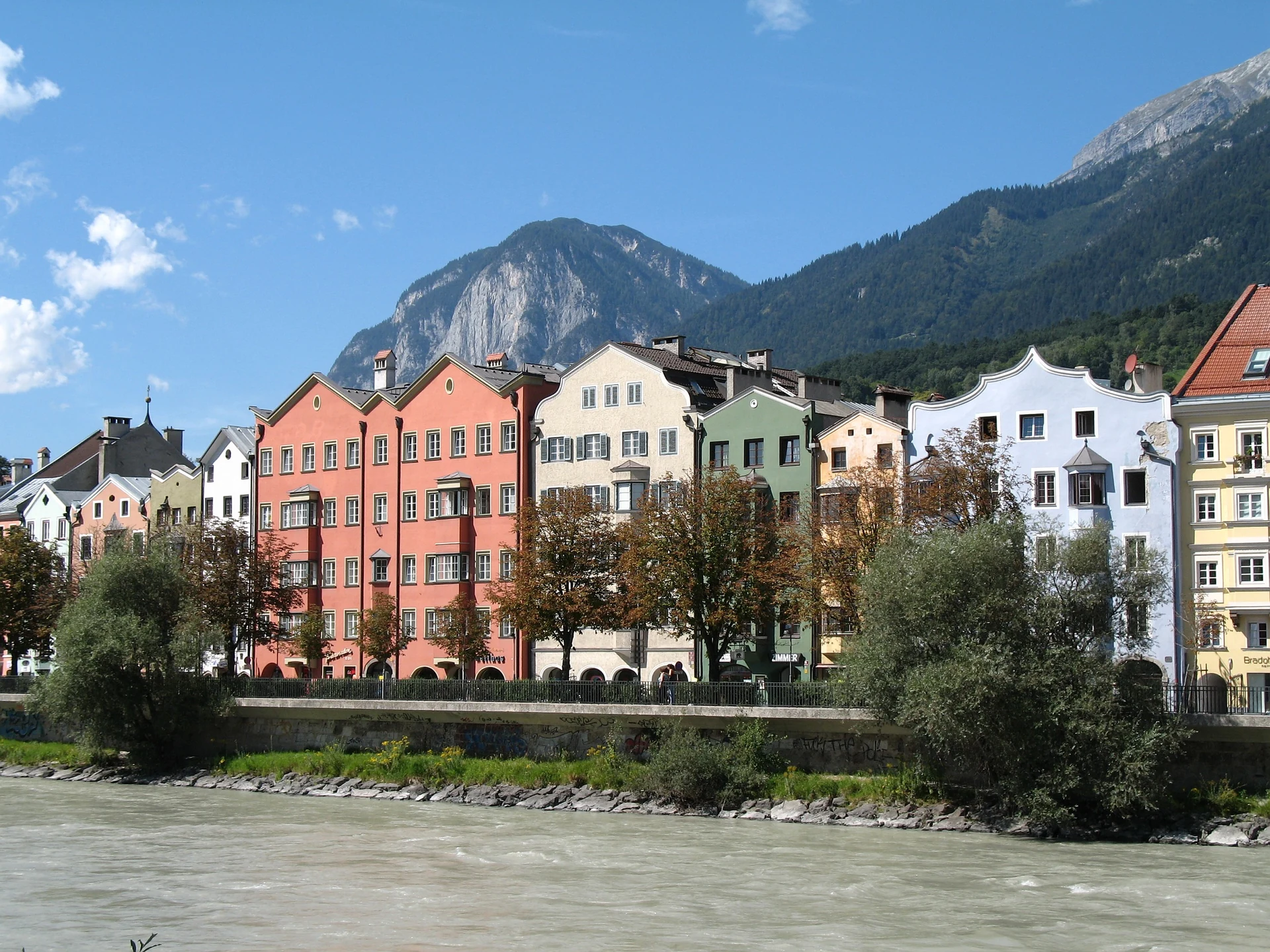 Colourful Mariahilf houses beside the Inn River with mountains behind Innsbruck