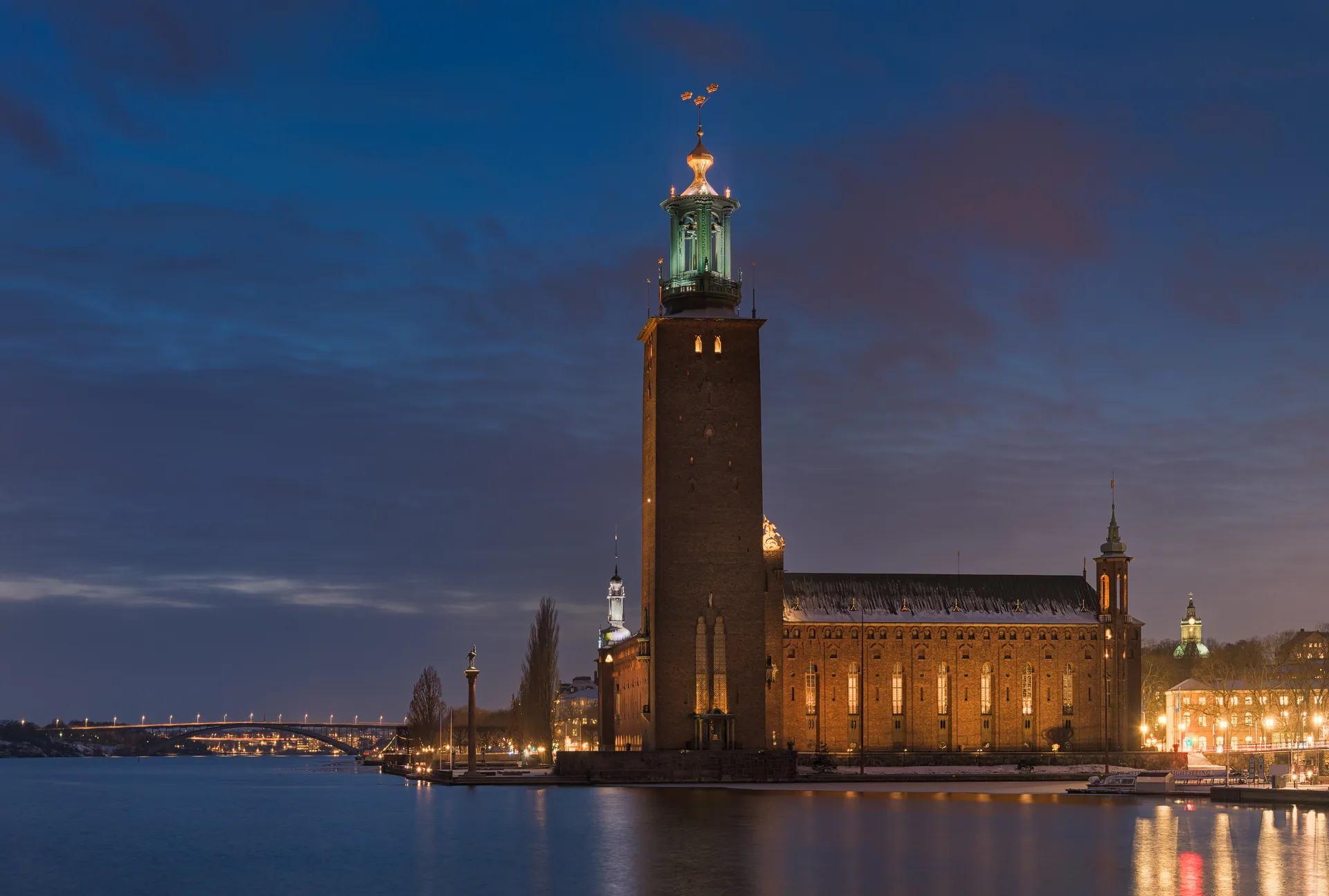 Stockholm City Hall illuminated above the water at winter blue hour