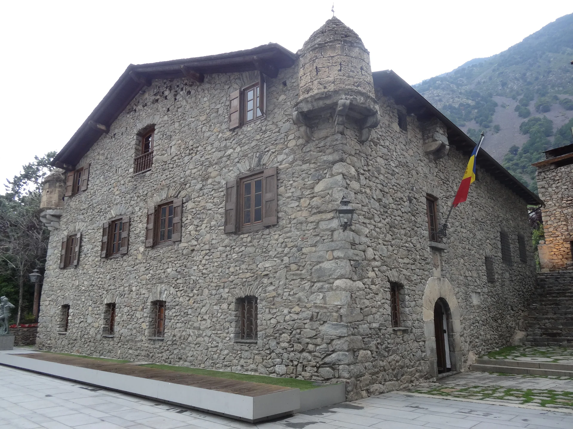 The stone facade and corner turret of Casa de la Vall in Andorra la Vella, with the Andorran flag