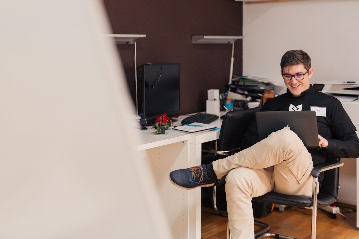 A smiling man working on a laptop in an office