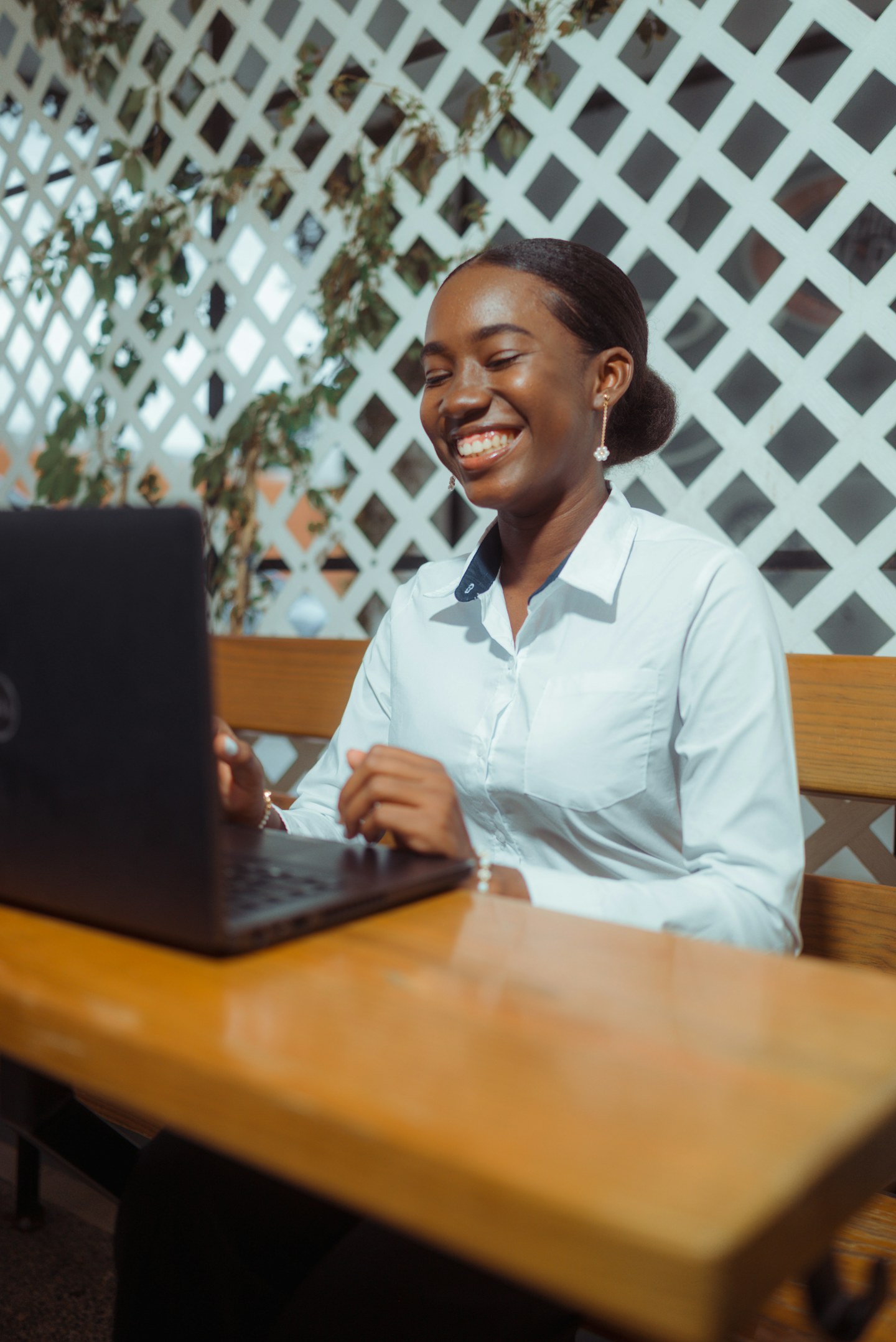 A smiling woman working on a laptop outdoors