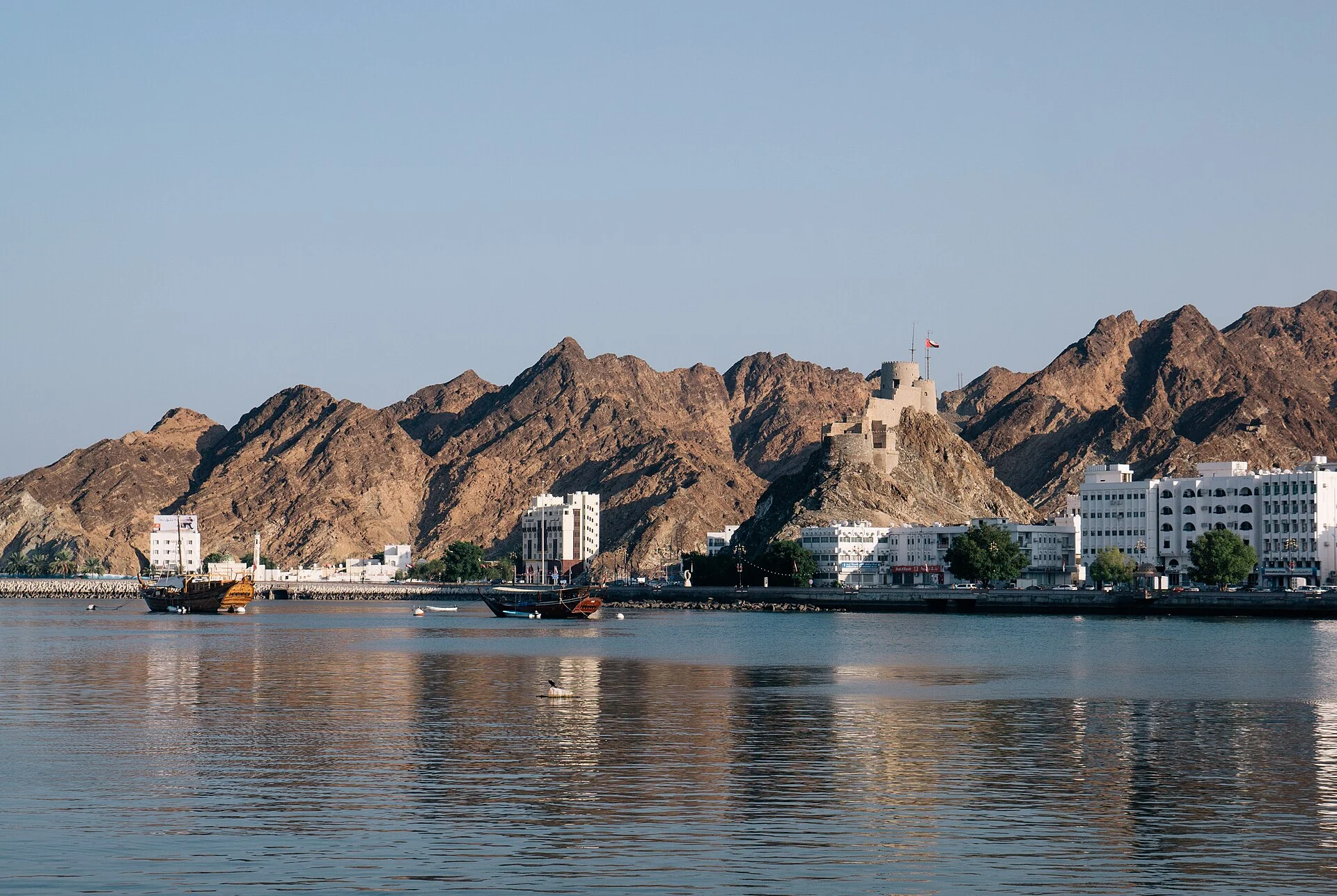 Muttrah Fort above the harbour and Corniche in Muscat, backed by rocky mountains