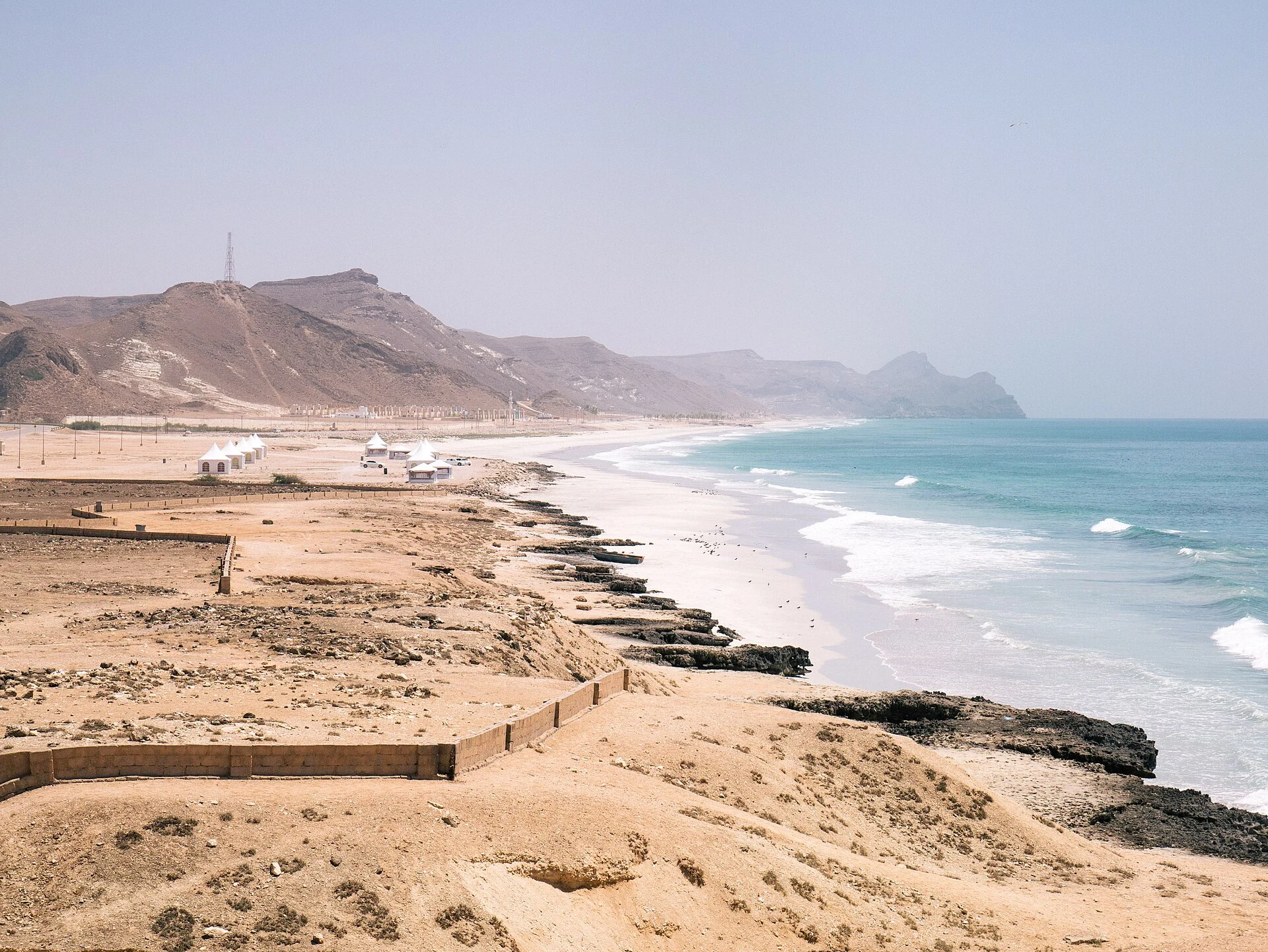 Mughsail’s beach and limestone coastline west of Salalah, with waves along the sandy shore