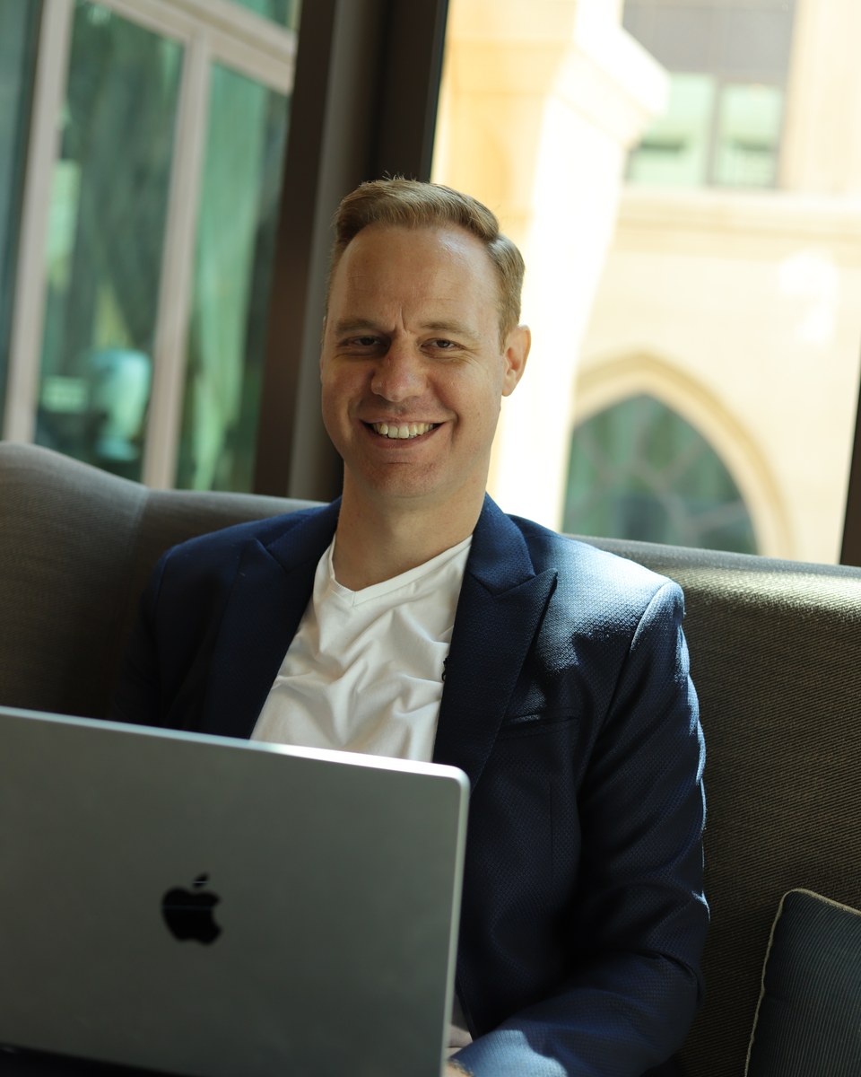 Michael Rosmer smiling beside his laptop